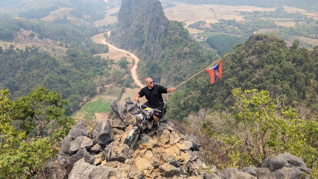 JC sitting on a motorbike on the edge of a cliff