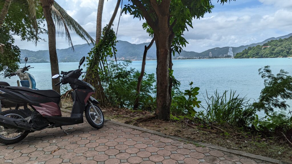 Motorbike parked near the waters edge looking across the bay to Patong Beach