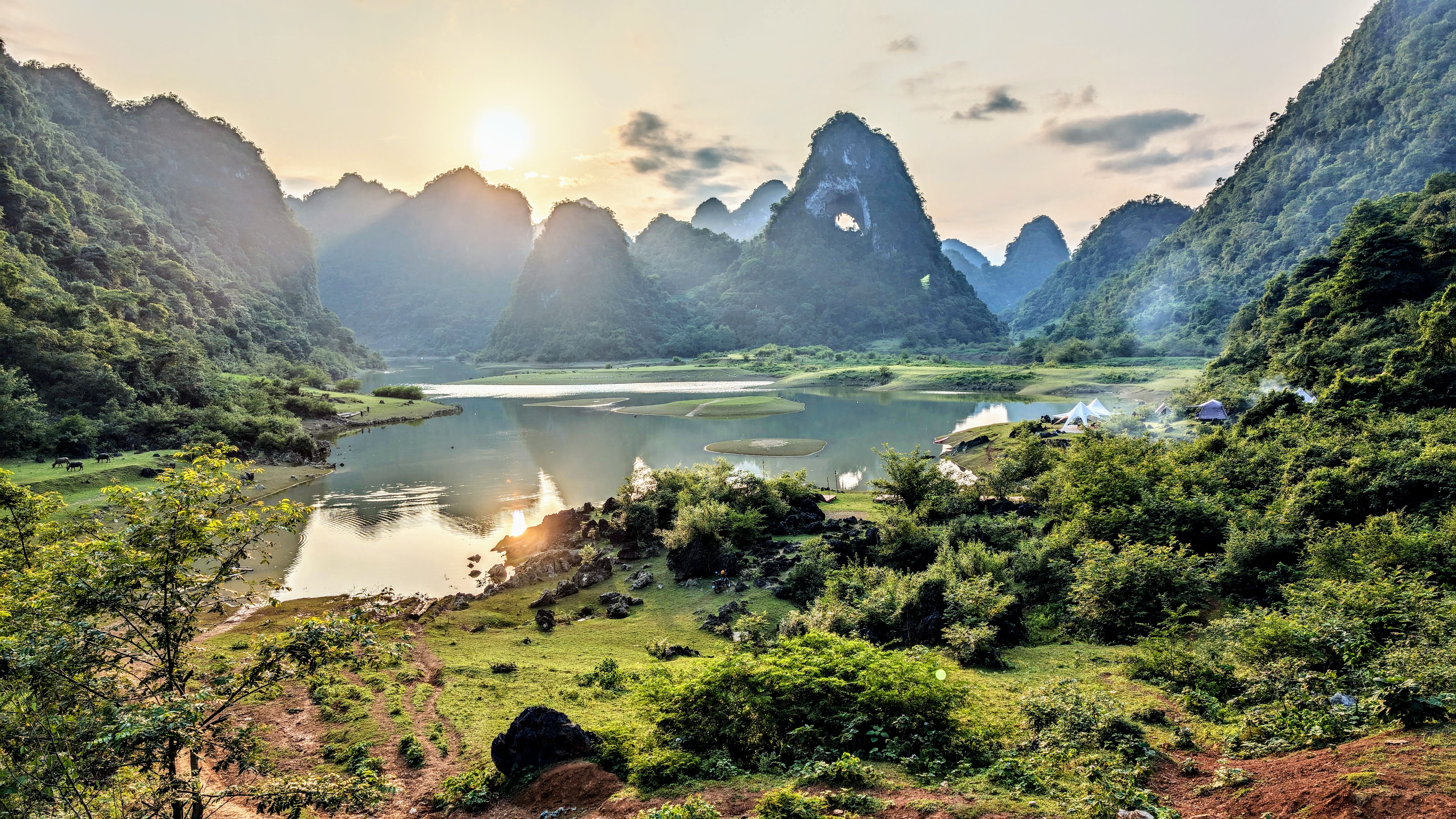 Looking over a lake Vietnam with a mountain in background with a hole in it.